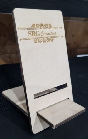 Wooden display stand holding a cream card with an ornate SRG Creations logo and decorative lines above and below the text, plus a slot for holding items at the bottom edge.