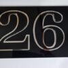 House number 26 in shiny metal digits on a black plaque.