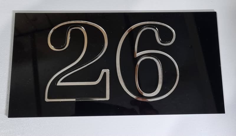 House number 26 in shiny metal digits on a black plaque.